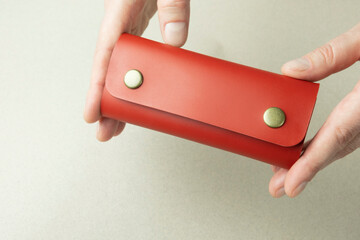 Wall Mural - bright red leather wallet in open female hands close-up on a gray background with shadows