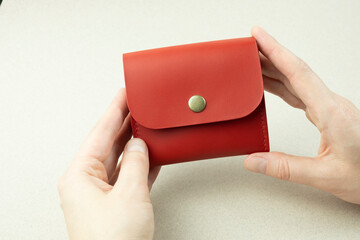 Wall Mural - red leather wallet in hands close-up on gray background