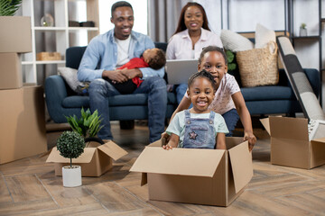 Wall Mural - Kids playing with boxes while parents relaxing on sofa