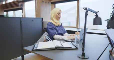 Wall Mural - Young Muslim female doctor
working on a laptop
