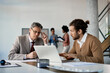 © Drazen - Executive manager mentors young trainee who works on laptop during internship at corporate office.