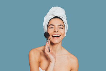 Wall Mural - Happy young woman wearing towel on her head holding makeup brush