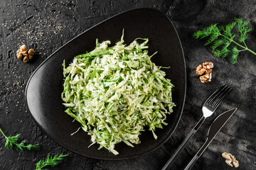 Wall Mural - Fresh salad with cabbage and herbs served on a plate over a dark background, top view. Concept of healthy food, clean eating