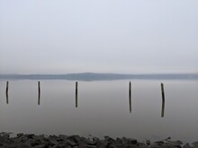 Wooden Posts In Sea Against Sky