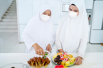 Wall Mural - Mother and daughter in face mask preparing foods