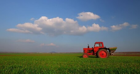 Wall Mural - Tractor fertilizing wheat field, working on agricultural fields 4k video