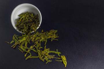 a bowl of green tea scattered on the black background with copy space