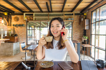 Wall Mural - Business casual women talking on smartphone while sitiing in cafe