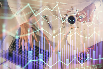 Multi exposure of man's hands typing over computer keyboard and forex graph hologram drawing. Top view. Financial markets concept.