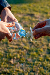 Person holds a pacifier in his hands, and the second pours water on her from a bottle (516)