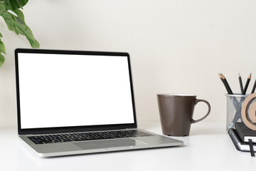 Wall Mural - Laptop computer with blank screen for mockup on modern contemporary workspace desk with coffee cup and office supplies. Home office workplace.