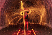 Beautiful Woman Holding An Umbrella Standing On Railway Tracks Surrounded By Spinning Wire Wool