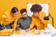 Group of multiracial cowrkers try to find mistake analyze drawbacks concentrated at paper document work together on common task pose at office desk against yellow background. Brainstroming concept
