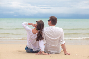 Wall Mural - Vacation couple sitting on beach together in love holding around each other