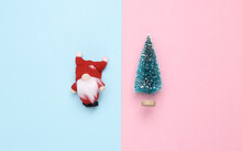 Christmas Gnome And Christmas Tree On Pink Blue Pastel Background. Top View