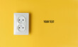 Double power socket on a yellow wall. Studio shot. Minimalism. Copy space