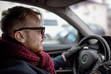 Wall Mural - fashionable male driver in sunglasses and a coat rides in the car