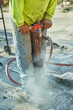 Worker on a concrete slab using a jackhammer to break concrete