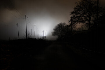 Wall Mural - night street country road with buildings and fences covered in fog lamp . or mysterious night in aze