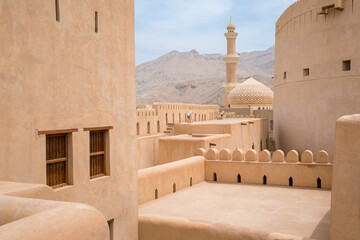 minaret, dome and walls of medievel arabian fort of nizwa, oman. hot day in arabian desert city. mid