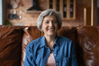 © fizkes - Active old age. Portrait of optimistic retired hispanic female clothed in stylish casual demonstrating perfect white teeth in beautiful smile. Energetic senior latin woman sit on couch look at camera