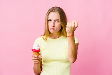 Wall Mural - Young russian woman eating an ice cream isolated showing fist to camera, aggressive facial expression.