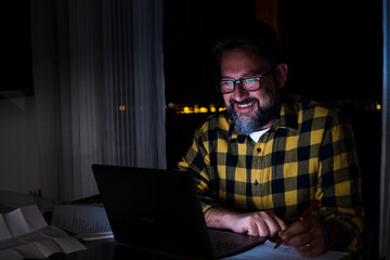 Wall Mural - Front view of male employee speak talk on video call with diverse colleagues on online event briefing. Man worker have group conference with coworkers on modern laptop at home at night..