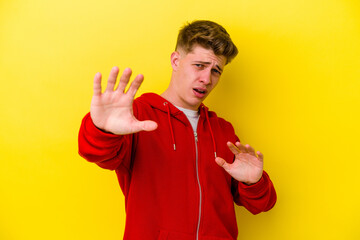 Young caucasian man isolated on yellow background being shocked due to an imminent danger