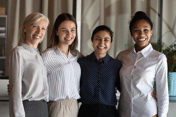 Poster - Happy diverse multiethnic female employees workers pose for team portrait in office together. Smiling multiracial women colleagues coworkers show leadership and unity. Teamwork, success concept.