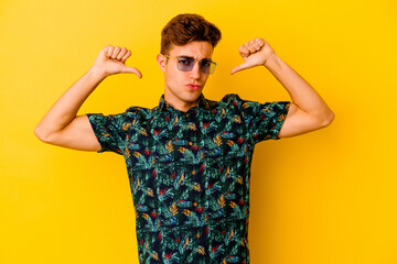 Young caucasian man wearing a Hawaiian shirt isolated on yellow background feels proud and self confident, example to follow.