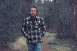 © ysbrandcosijn - Cheerful blonde man in checkered coat walking on a path in a forest.