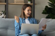 Close up overjoyed woman reading good news in paper letter sitting on couch with laptop on laps at home, excited by money refund, job promotion, happy young female student getting scholarship