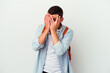 © Asier - Young caucasian student man listening to music isolated on white background blink through fingers frightened and nervous.