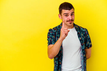 Young caucasian cool man isolated on yellow background showing number one with finger.