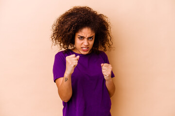 Wall Mural - Young african american woman isolated on beige background upset screaming with tense hands.