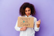 © Asier - Young African American woman holding a girl power placard isolated on purple background pointing with finger at you as if inviting come closer.