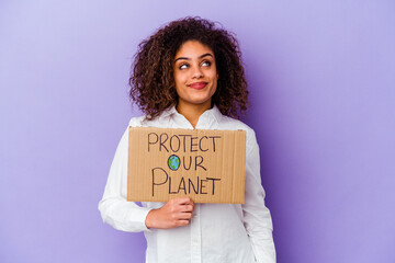 Wall Mural - Young African American woman holding a girl power placard isolated on purple background dreaming of achieving goals and purposes