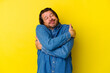 Middle age caucasian man isolated on yellow background hugs, smiling carefree and happy.