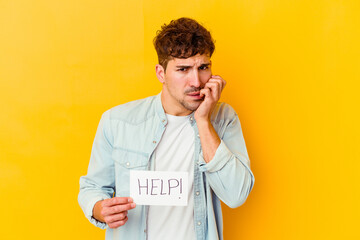 Wall Mural - Young caucasian man holding a help placard isolated biting fingernails, nervous and very anxious.