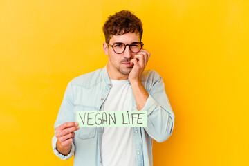 Wall Mural - Young caucasian man holding a vegan life placard isolated biting fingernails, nervous and very anxious.