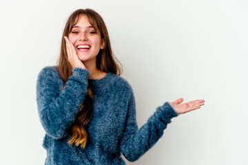 Young caucasian cute woman isolated on white background holds copy space on a palm, keep hand over cheek. Amazed and delighted.