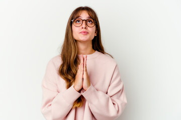 Wall Mural - Young caucasian cute woman isolated on white background holding hands in pray near mouth, feels confident.