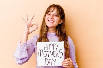 Wall Mural - Young caucasian woman holding a Happy mothers day placard isolated cheerful and confident showing ok gesture.