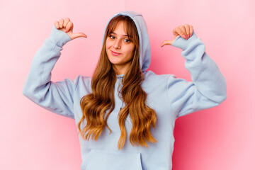 Young caucasian woman with hood isolated on yellow background feels proud and self confident, example to follow.