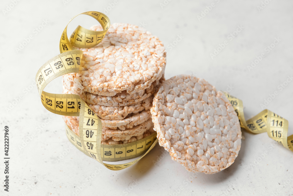Rice crackers and measuring tape on light background