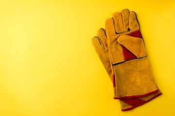 Wall Mural - Yellow protective construction gloves on yellow background.