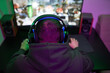 © snedorez - Gamer or streamer in headphones with microphone sits at home in neon light and plays at pc