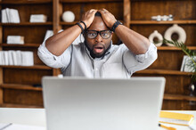 African American Businessman Received Email With Bad News, Sitting At The Desk With Laptop, Lost Business, Office Worker Made Mistake, Feeling Scared And Stressed, Holding Head In Hands And Screaming
