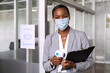 © Rido - Businesswoman with face mask taking temperature at office entrance