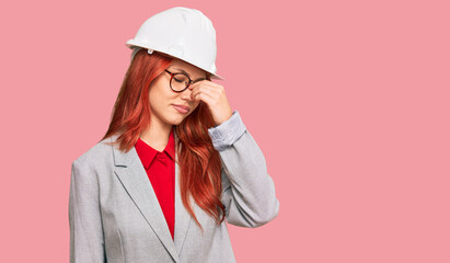 Canvas Print - Young redhead woman wearing architect hardhat tired rubbing nose and eyes feeling fatigue and headache. stress and frustration concept.